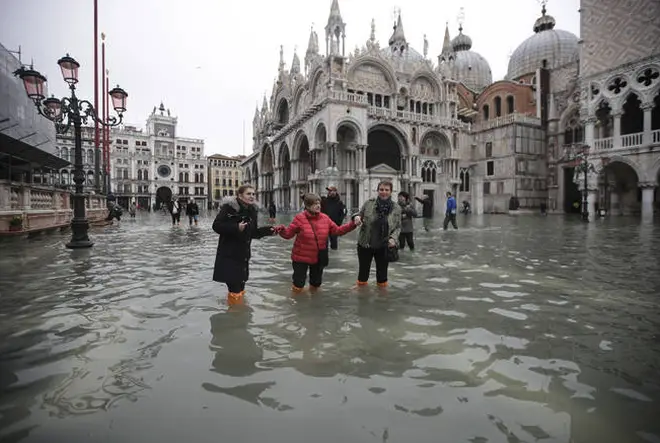 People wade through water in a flooded St. Mark's Square in Venice.