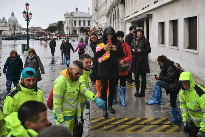 Volunteers set up a footbridge for pedestrians across the flooded Riva degli Schiavoni embankment.