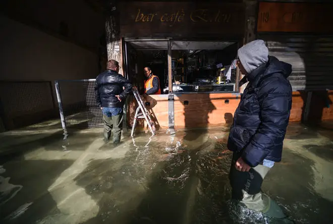 A man walks past a cafe across a flooded arcade by St. Mark's Square.