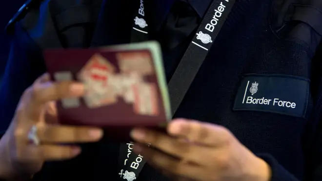 A UK Border Force agent inspects a passport