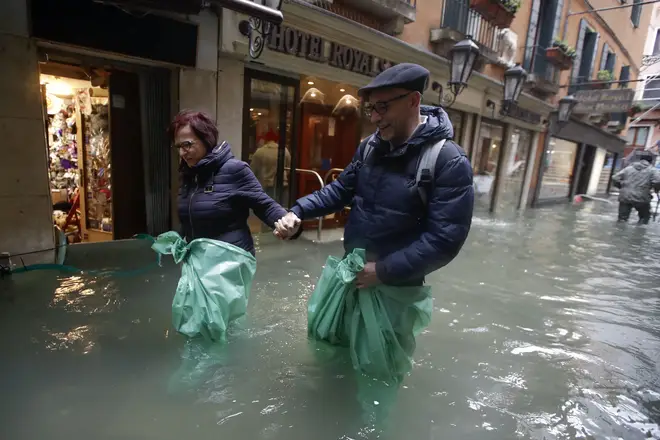 A couple wades their way through water in Venice