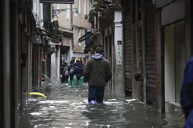 People wade their way through flooded streets in Venice