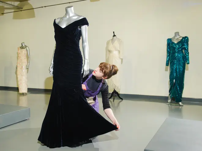 House assistant Lucy Bishop adjusts a midnight-blue velvet Victor Edelstein evening gown, at Kerry Taylor Auctions