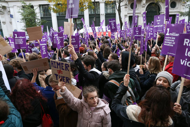 Women in Paris hold purple flags and signs during a protest to condemn violence against women