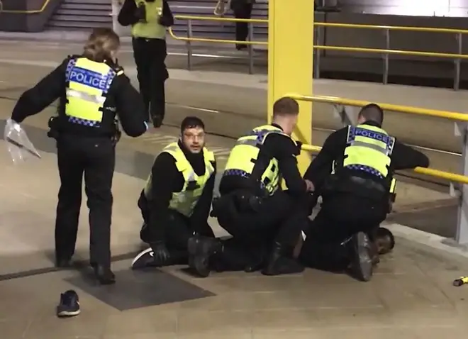 Police restraining a man after he stabbed three people at Victoria Station in Manchester.