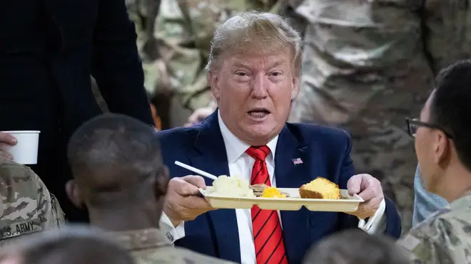 President Donald Trump holds up a tray of Thanksgiving dinner during a surprise Thanksgiving Day visit to the troops